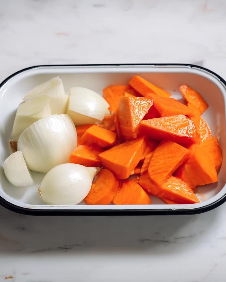 In a white rectangular tray with a black rim, there are two layers of sliced vegetables: the front layer has bright orange carrot pieces cut into uneven triangular shapes with smooth, shiny surfaces, while behind them there are whole onions cut into large chunks with a pale white color and smooth texture. The tray is placed on a white marbled surface, giving a clean and simple look. Photo taken with an iphone --ar 4:5 --v 7