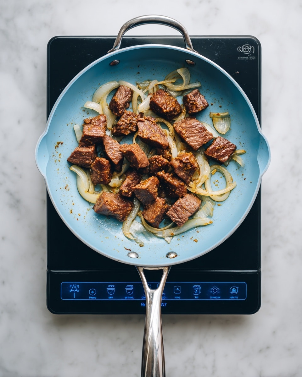 A light blue frying pan with a silver handle sits on a black induction cooktop with a blue digital screen. Inside the pan, there are several pieces of brown cooked liver with a slightly rough texture, mixed with translucent, light yellow cooked onion rings scattered evenly across and under the liver pieces. The cooktop and pan rest on a white marbled surface, creating a clean background. Photo taken with an iphone --ar 4:5 --v 7