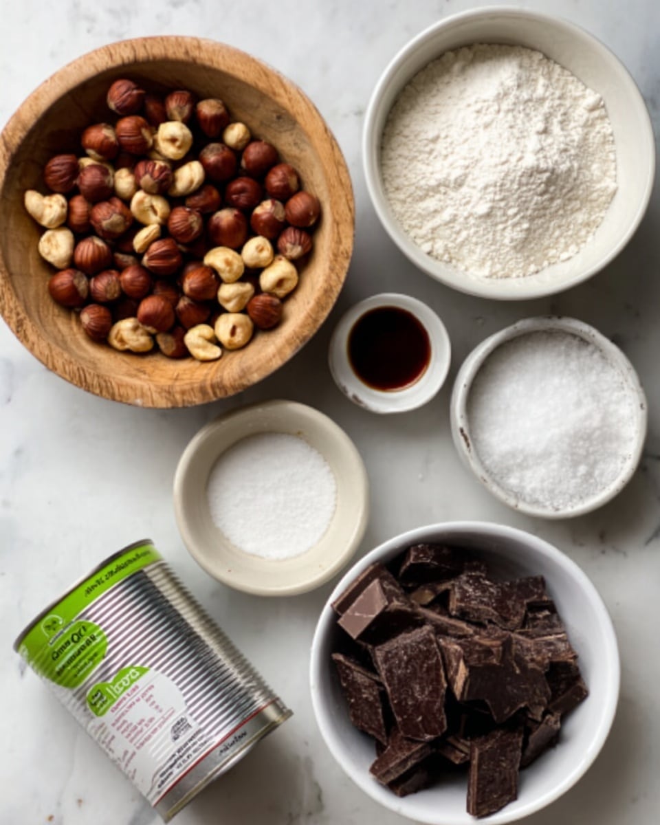 A white marbled surface holds six containers with baking ingredients arranged neatly. Starting from the top left, a round wooden bowl is filled with mixed nuts, mostly brown and beige hazelnuts. To its right, a white bowl holds smooth, white flour. Below the nuts, a small white cup contains a dark brown liquid, possibly vanilla extract. Beside it, a tiny white dish has fine white salt. A white bowl at the bottom right is filled with uneven chunks of dark brown chocolate. Near the bottom left is a silver can with a green and white label lying on its side, showing coconut milk. On the far right, a small white dish holds white granulated sugar. The photo taken with an iphone --ar 4:5 --v 7