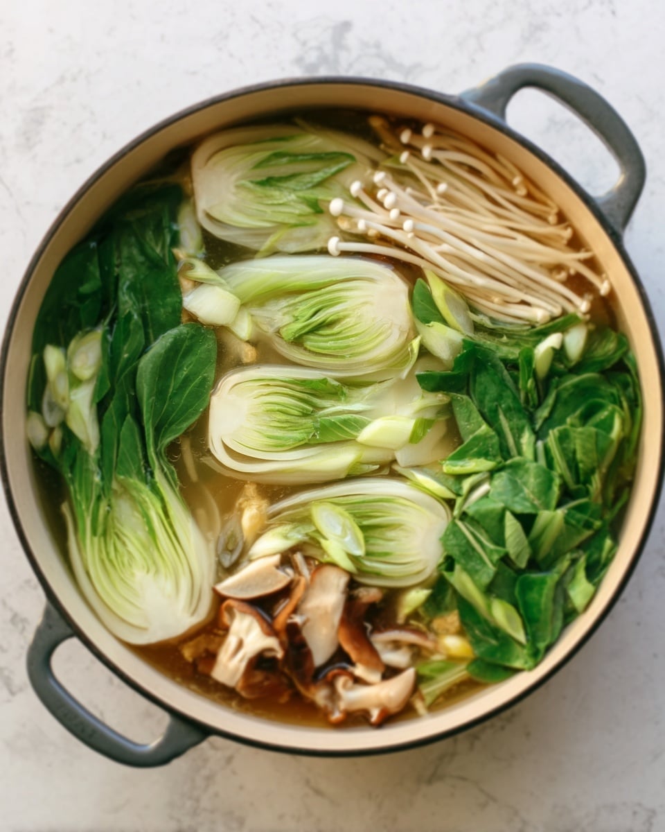 The image shows a pot filled with clear broth and fresh vegetables arranged in layers. The bottom layer has light green baby bok choy with smooth, rounded leaves positioned around the edges. On top of this, there are thin, white enoki mushrooms with long stems, mixed with small clusters of light brown oyster mushrooms that have a soft texture. Some pieces of green leafy veggies are placed on one side, adding a rich green color. The pot is on a white marbled surface, and the broth is clear, showing all the vegetables through it. Photo taken with an iphone --ar 4:5 --v 7