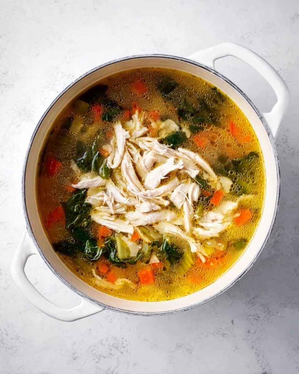 A white pot filled with clear broth soup, showing layers of ingredients inside. At the bottom layer are small orange carrot pieces, green leafy spinach, and light green celery chunks. On top is a layer of shredded white chicken, placed in the center of the soup. The pot sits on a white marbled surface, and the soup liquid has a golden-yellow tint. The scene is simple and clean, showing the fresh and healthy look of the soup. photo taken with an iphone --ar 4:5 --v 7
