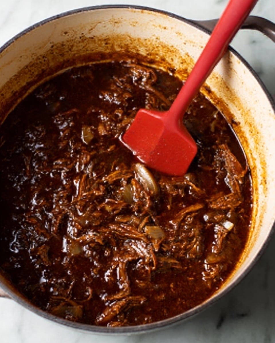 The image shows a close-up of dark brown stew with soft, shredded pieces of meat in a white pot. The stew looks thick and rich, with visible bits of onion mixed in. A red silicone spatula is partially dipped into the stew, resting inside the pot. The pot is placed on a white marbled surface, and the texture of the stew appears moist and tender. Photo taken with an iphone --ar 4:5 --v 7