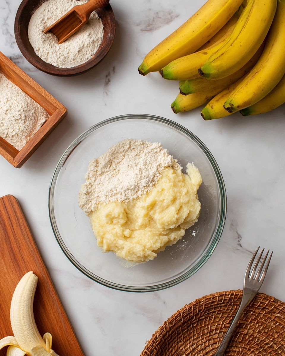 A clear glass bowl sits on a white marbled surface, holding two separate layers of soft ingredients; the top layer is a light, grainy white mixture with a slightly crumbly texture, while the bottom layer is mashed ripe bananas in a smooth and creamy pale yellow color. To the top right of the bowl, a bunch of yellow bananas rests with greenish tones near the stems. Above the bowl, a dark wooden bowl contains light beige flour with a small wooden scoop inside. At the bottom left, a wooden cutting board holds a peeled section of banana with the yellow peel curled beside it. On the right side, the tip of a silver fork leans on the white marbled surface near the edge of a woven basket. photo taken with an iphone --ar 4:5 --v 7