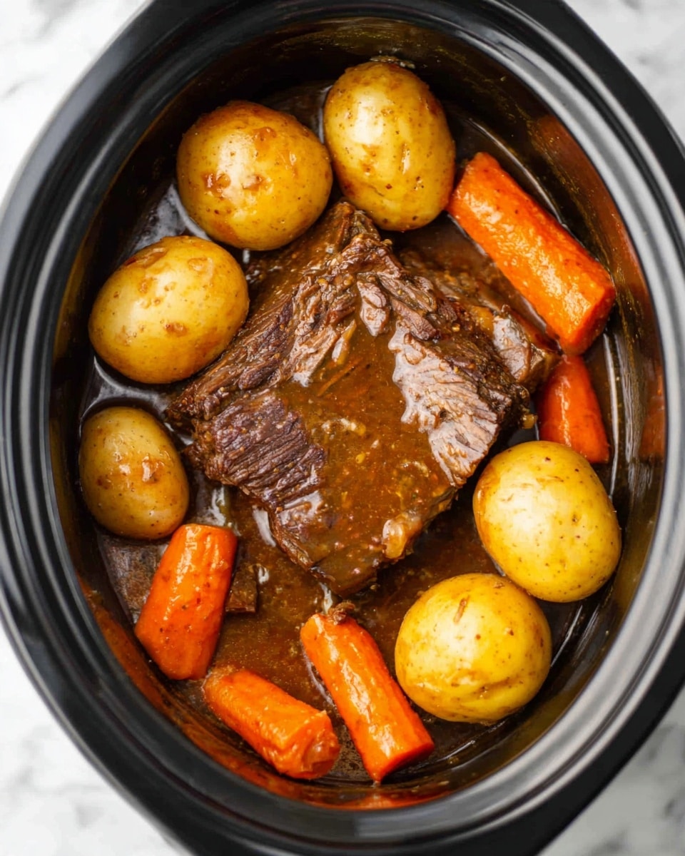 The image shows a dark slow cooker filled with a cooked beef piece in the center, covered in thick brown gravy. Around the beef, there are small whole golden potatoes and bright orange carrot sticks, all cooked and slightly shiny from the sauce. The potatoes have a smooth surface with some skin visible, and the carrots are smooth and firm looking. The slow cooker sits on a white marbled surface. Photo taken with an iphone --ar 4:5 --v 7