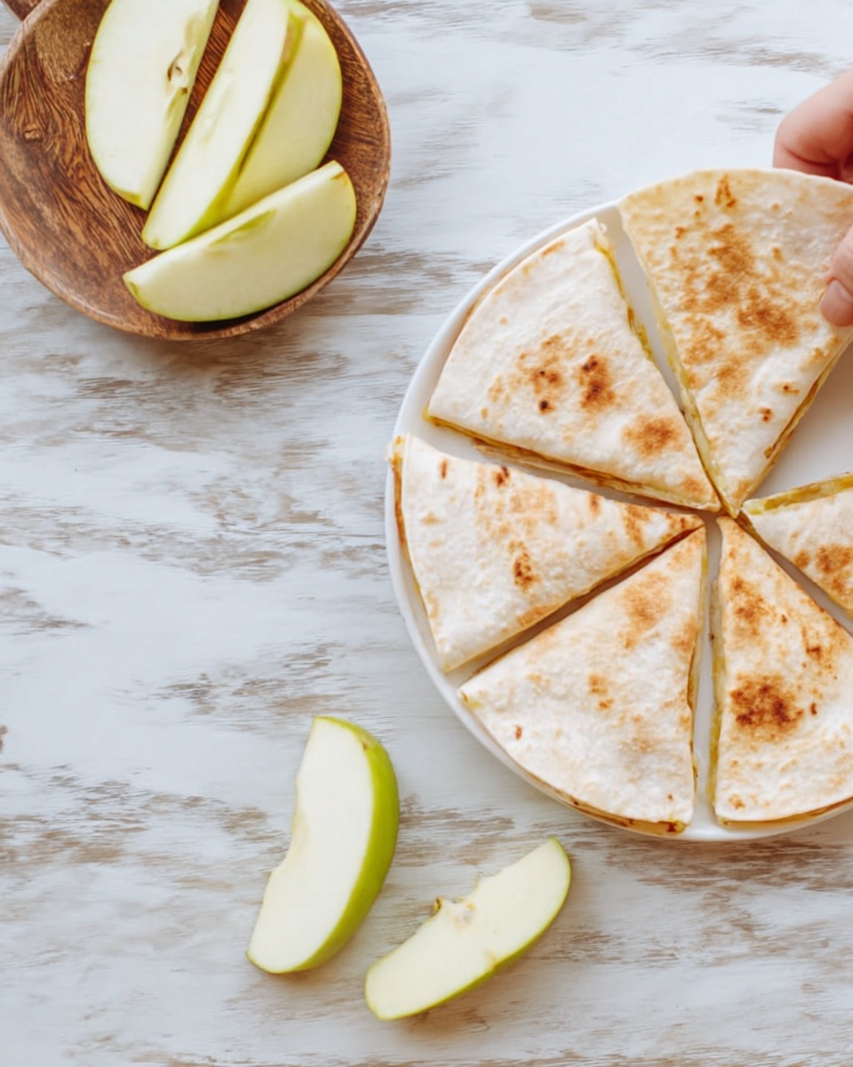 A white plate on a white marbled surface holds a flat, round, light brown tortilla divided evenly into six triangle slices showing slight toasted marks. To the side, slices of green apple rest directly on the white marbled surface, some leaning and others flat, with uneven edges. A woman's hand is holding one quarter of the tortilla near a small wooden tray that holds more tortilla slices. photo taken with an iphone --ar 4:5 --v 7