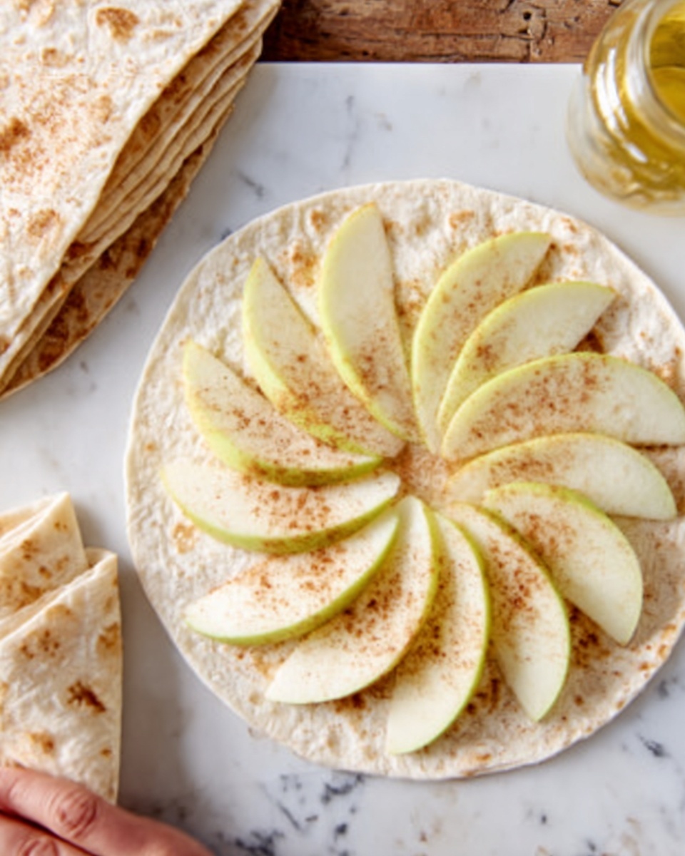 The image shows a round soft tortilla placed flat on a white marbled surface, topped with a single layer of thin, pale green apple slices arranged in a circle like flower petals. The apple slices have a light dusting of brown cinnamon powder evenly spread on them, adding subtle texture and color. To the left, there are folded tortillas stacked on the white marbled surface. A woman's hand is partially visible near the top left corner, gently holding one of the folded tortillas. photo taken with an iphone --ar 4:5 --v 7