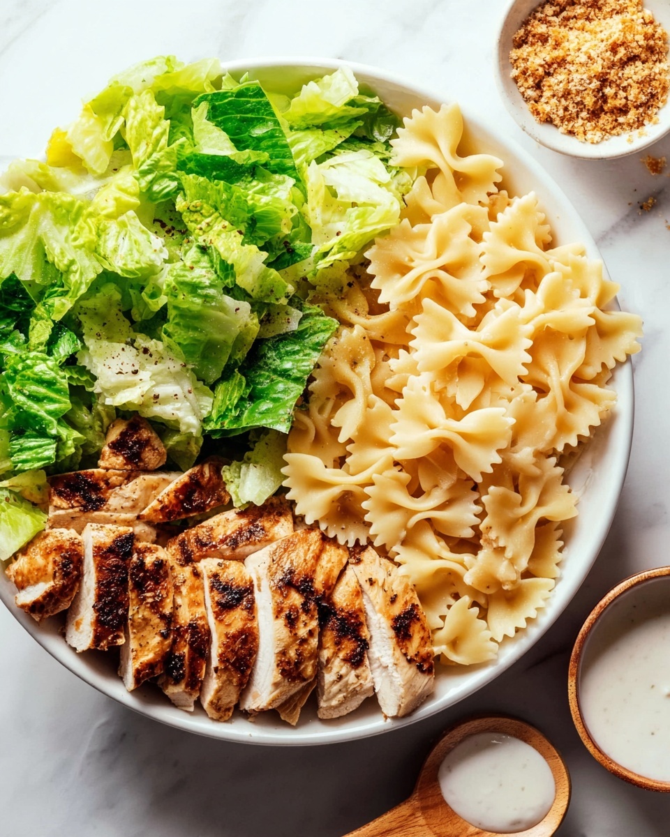 A white bowl sits on a white marbled surface filled with three sections: bright green leafy lettuce on the top left, light golden farfalle pasta on the right with a smooth texture and ruffled edges, and light brown grilled chicken slices at the bottom left showing some char marks and a slightly rough texture. In the upper right corner, a small round bowl contains light brown crumbs. Below the main bowl, there is a small bowl of white creamy dressing with a woman's hand holding a small wooden spoon beside it. Photo taken with an iphone --ar 4:5 --v 7
