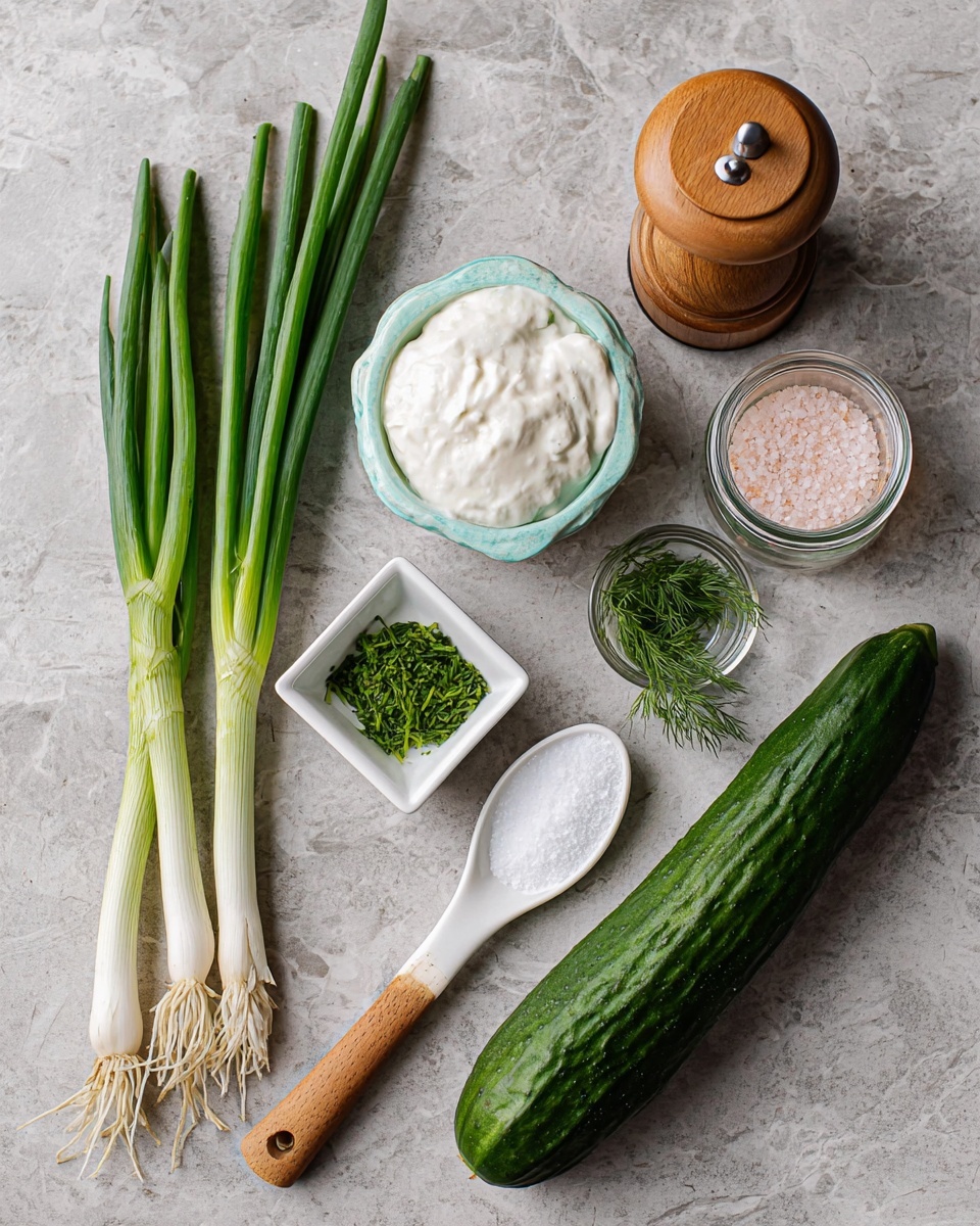 The image shows fresh ingredients placed on a white marbled surface. On the left side, there are three green onions with long green leaves and white roots. Next to them is a light blue ceramic spoon filled with thick white cream. Below it is a small white measuring spoon with white salt. In the middle, there is a small white square dish containing bright green chopped dill and a clear glass bowl with water. A wooden pepper grinder and a round wooden jar with pink salt and an open lid are placed to the right. A long, dark green cucumber lies horizontally on the right side of the image. Photo taken with an iphone --ar 4:5 --v 7