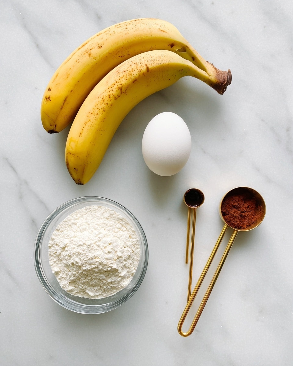 The image shows five raw ingredients arranged on a white marbled surface: two yellow bananas with some brown spots on their skin, one white egg placed to the right of the bananas, a small clear glass bowl filled with white flour positioned below the bananas, and two gold measuring spoons lying next to each other on the right side. One spoon contains a small amount of dark liquid, and the other spoon holds a reddish-brown powder. photo taken with an iphone --ar 4:5 --v 7