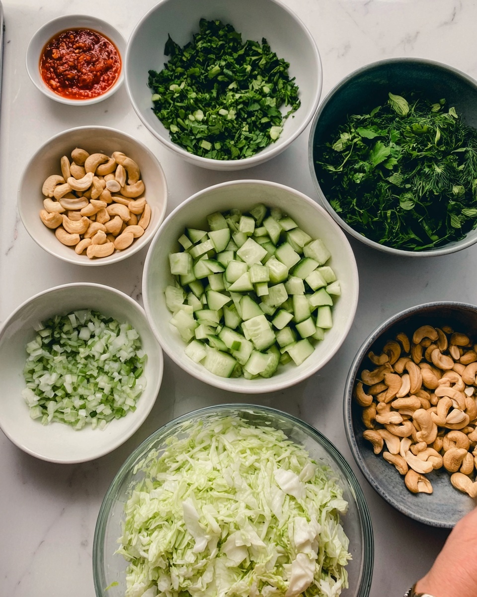 The image shows seven white bowls with different ingredients placed on a white marbled surface. At the bottom right, there is a clear glass bowl filled with finely chopped white cabbage. Below it and to the left is a white bowl filled with small green cucumber pieces. Above this is a white bowl with chopped green herbs. To the right is a gray bowl filled with large green leafy herbs. Above the gray bowl, there is another white bowl filled with whole light brown cashews. At the top left, a small white bowl contains a bit of red chili sauce, and next to it is a white bowl filled with chopped flat green herbs. A woman's hand is about to pick something from the bowls. Photo taken with an iphone --ar 4:5 --v 7