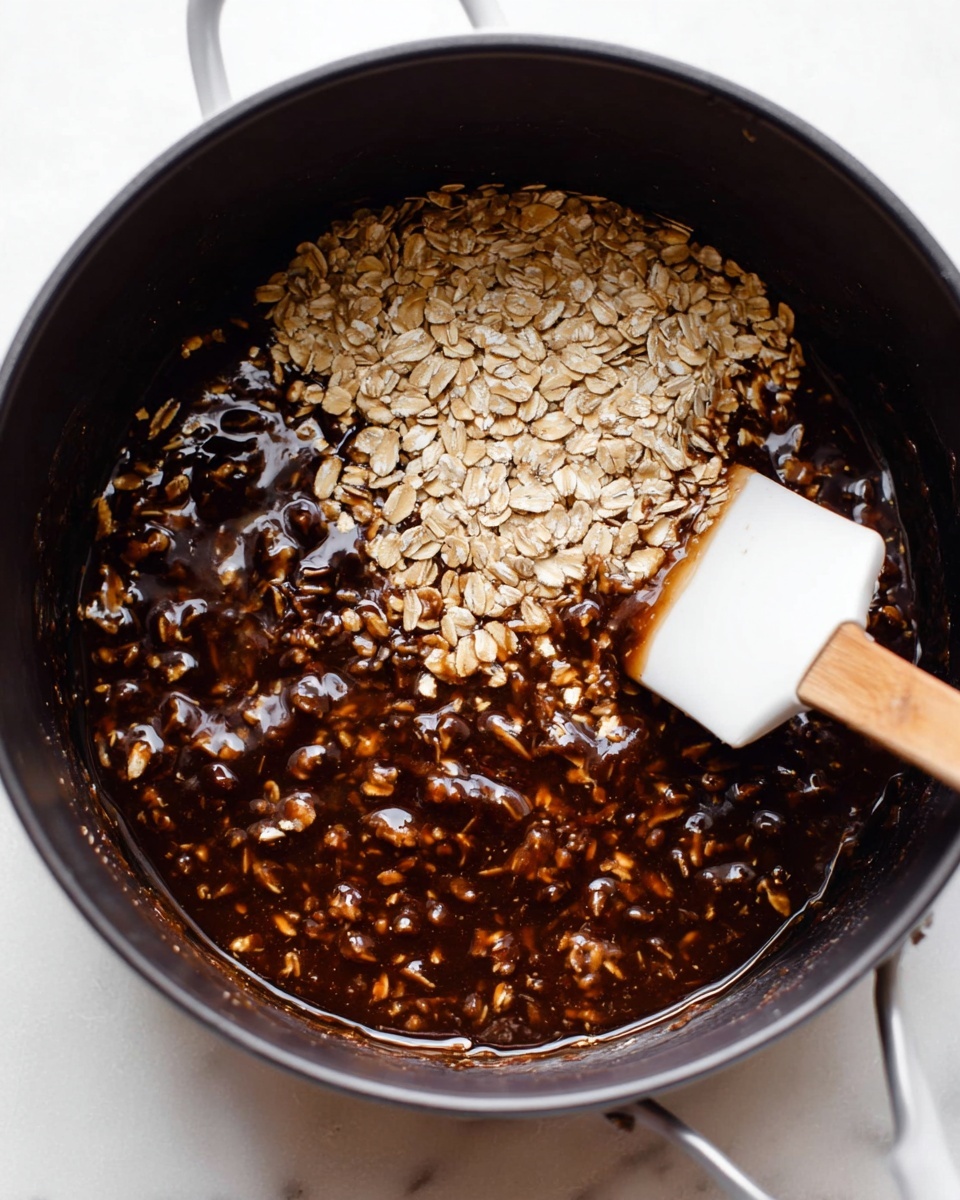 The image shows a close-up view of a black pot filled with a mixture of oats and thick, dark brown syrup. Some of the oats remain dry and light beige, while others are coated in the glossy syrup, which has a smooth, sticky texture. A white spatula with a wooden handle is partially submerged in the pot, stirring the mixture from the right side. The pot sits on a white marbled surface, adding a clean and bright contrast to the rich colors of the mixture. Photo taken with an iphone --ar 4:5 --v 7