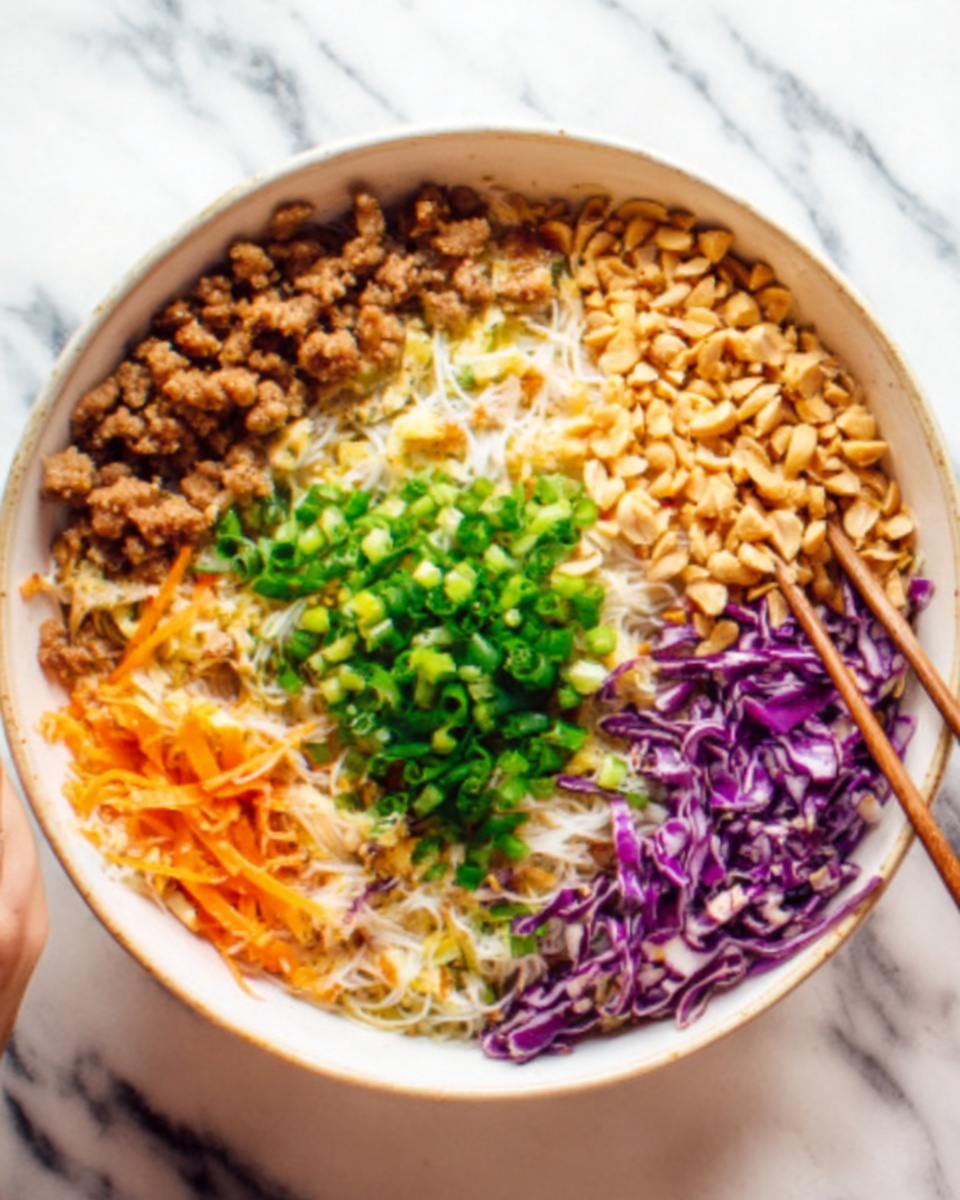 A white bowl filled with a colorful layered dish. The bottom layer consists of thin noodles mixed with purple cabbage and carrot shreds, giving a soft texture with white, purple, and orange colors. Above the noodles, there are three clear sections: on the left, small brown cooked meat pieces; in the middle, finely chopped green onions that add a bright green color; and on the right, a layer of crunchy light brown peanuts. A woman's hand is holding a pair of chopsticks reaching into the bowl. The bowl sits on a white marbled surface. photo taken with an iphone --ar 4:5 --v 7