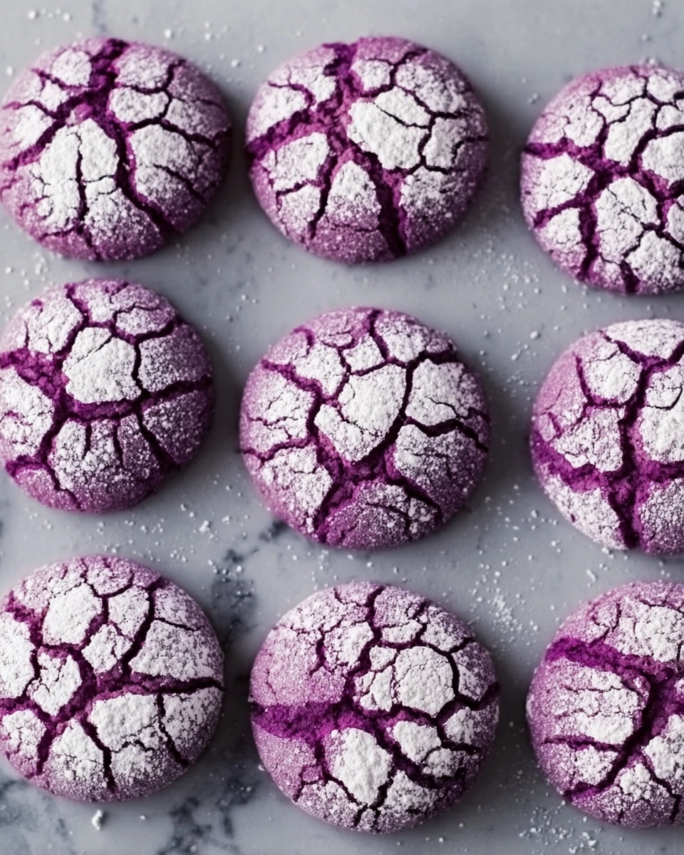 The image shows nine round purple cookies with a cracked pattern on top, dusted with white powdered sugar that fills the cracks, creating a contrast between the deep purple and bright white. The cookies are laid out in a 3 by 3 arrangement on a grey baking sheet, which rests on a white marbled surface. Each cookie has a slightly rough texture with visible cracks, and all cookies are evenly spaced and uniform in size. photo taken with an iphone --ar 4:5 --v 7
