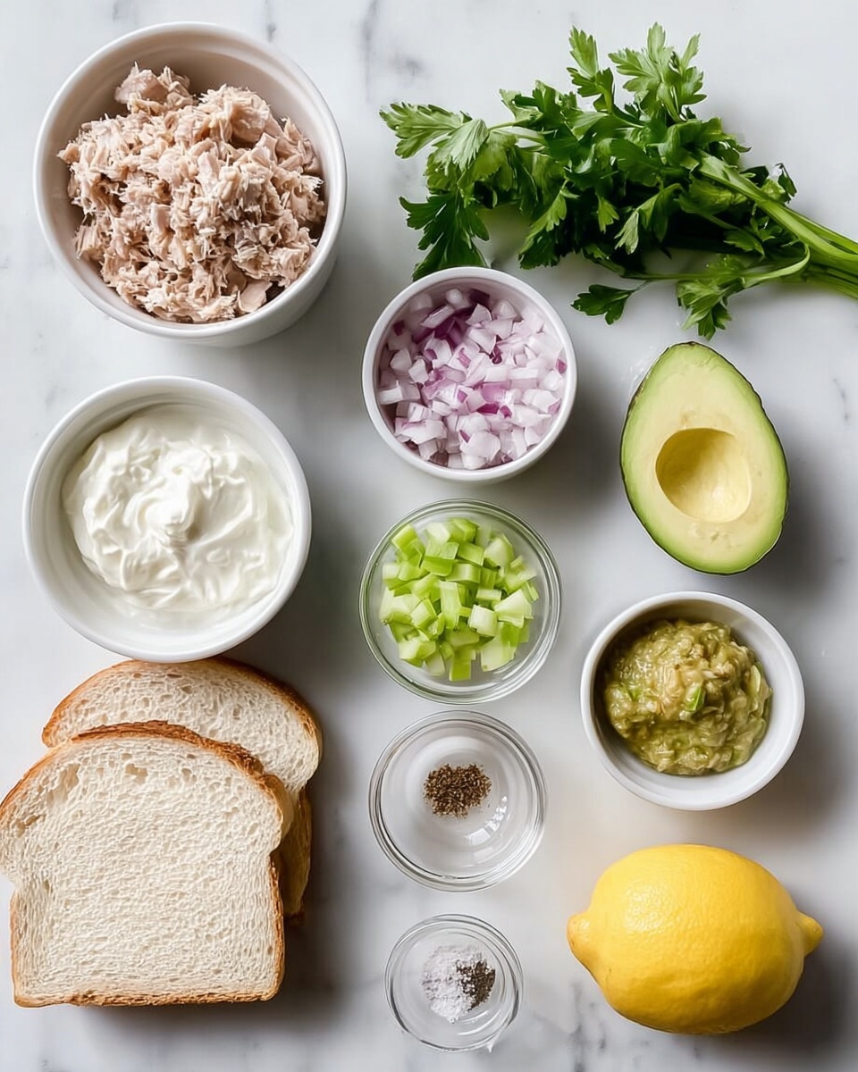 The image shows several small white bowls on a white marbled surface, each holding different ingredients: shredded light brown tuna in one bowl, chopped red onion in another, creamy white yogurt in a third, finely chopped light green celery in a fourth, green chili paste in a fifth, and yellow mustard in a sixth. Next to these bowls, there is a halved avocado with a visible dark brown seed, two slices of light beige bread with a soft crumb, a small bunch of fresh green parsley, a bright yellow lemon, and a tiny clear dish containing salt, black pepper, and a light brown spice. photo taken with an iphone --ar 4:5 --v 7