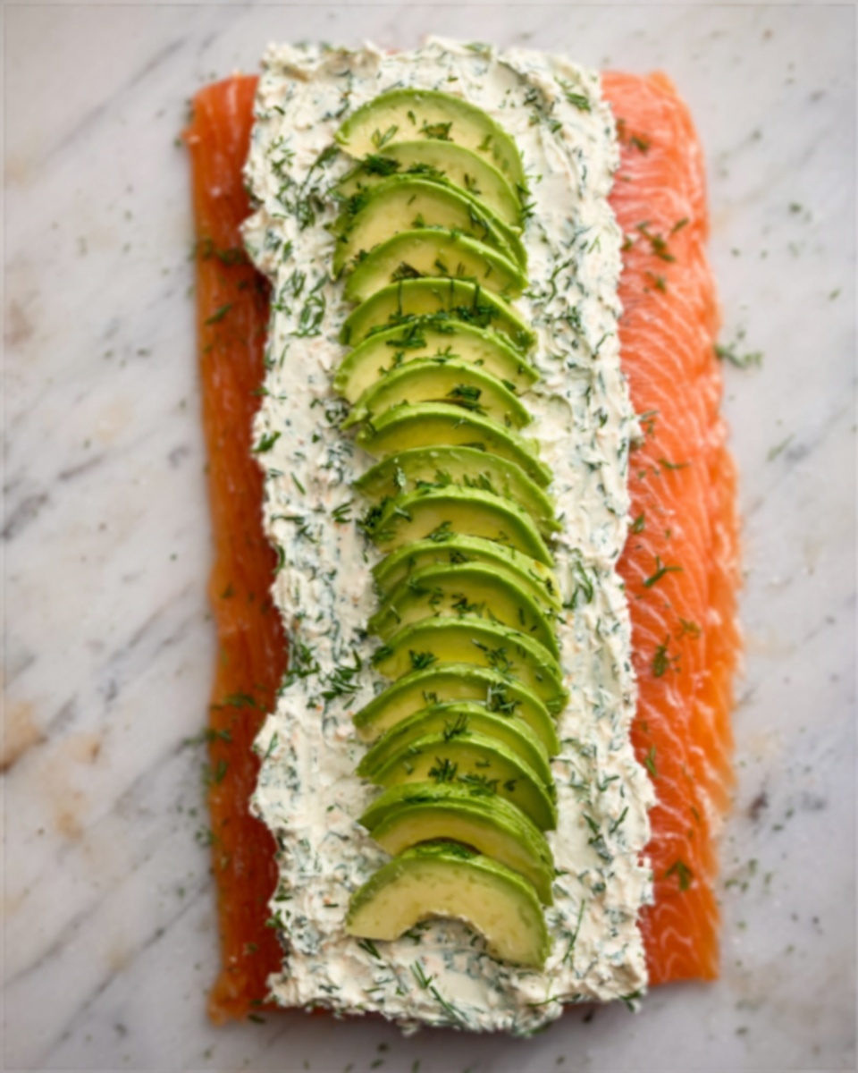 The dish shows a flat piece of orange salmon laid flat on a white marbled surface. On top of the salmon, there is a thick layer of creamy white spread with green herb bits mixed throughout. In the middle of this layer, slices of green avocado are neatly arranged in a line, slightly overlapping each other from top to bottom. The entire setup looks fresh and colorful. photo taken with an iphone --ar 4:5 --v 7