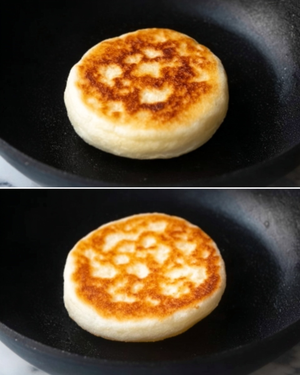 The image shows two close-up shots of a single small round bread cooking on a black pan. The bread has a light golden-brown top layer, which looks soft and slightly puffy with some air bubbles. The edges of the bread are white and fluffy, creating a soft contrast with the golden center. The bread sits in the middle of the pan, which has a matte surface. The background under the pan is a white marbled texture. photo taken with an iphone --ar 4:5 --v 7