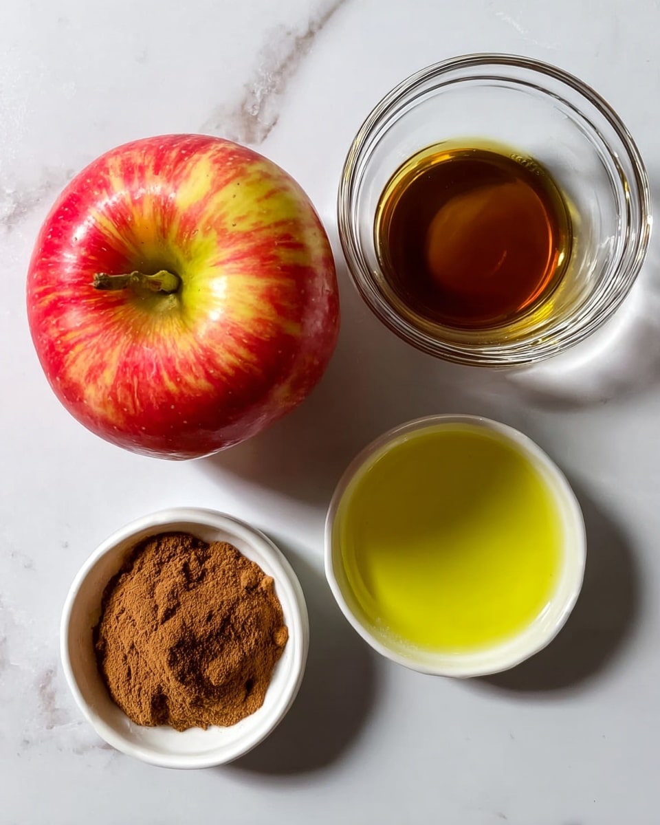 The image shows four items placed on a white marbled surface. On the left is a whole red and yellow apple with a visible stem at the top. To the right of the apple, there is a small clear glass bowl filled with a brown liquid. Below the apple is another small clear glass bowl filled with brown cinnamon powder. Below the brown liquid bowl, there is a white bowl filled with light yellow oil. The items are neatly arranged in a square shape. photo taken with an iphone --ar 4:5 --v 7