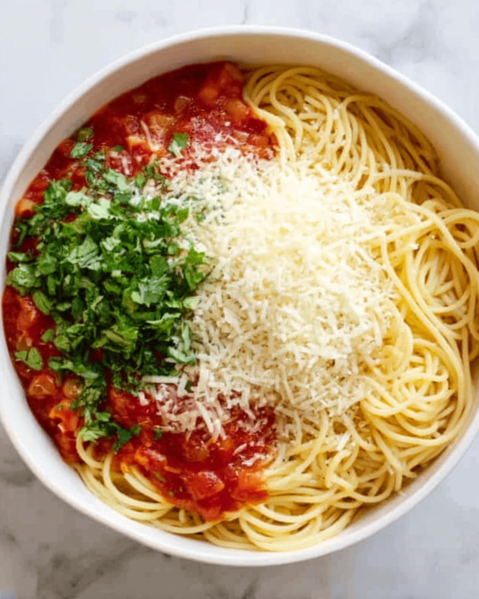 A white bowl filled with spaghetti pasta covered with red tomato sauce at the bottom. On top, the spaghetti is divided into two main sections: fresh green chopped herbs on the left and a pile of grated light yellow cheese on the right. The textures show the smooth sauce, the soft spaghetti strands, the leafy herbs, and the finely shredded cheese. The bowl is placed on a white marbled surface. photo taken with an iphone --ar 4:5 --v 7