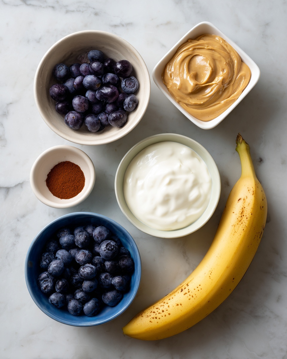 A white marbled surface holds six items arranged in a loose circle: a whole yellow banana with some brown spots on the right, a small square white bowl filled with light brown peanut butter with a smooth texture, a small blue bowl filled with dark blue, plump blueberries, a small white bowl with creamy white yogurt, a small white bowl with clear liquid, and a small white bowl containing a reddish-brown powder, all evenly spaced. photo taken with an iphone --ar 4:5 --v 7