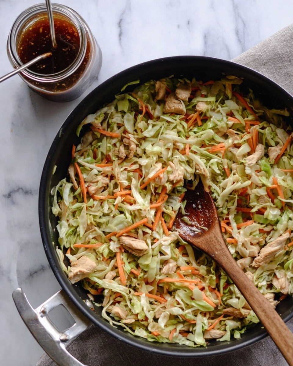 A black pan filled with a colorful mix of shredded light green cabbage, thin orange carrot strips, and small pieces of light brown cooked chicken, all mixed evenly. A wooden spoon rests inside the pan, slightly stained from the food. To the top left of the pan, there is a glass jar with a dark brown sauce and a metal straw sticking out. The pan and jar are placed on a white marbled surface with a soft pattern. photo taken with an iphone --ar 4:5 --v 7