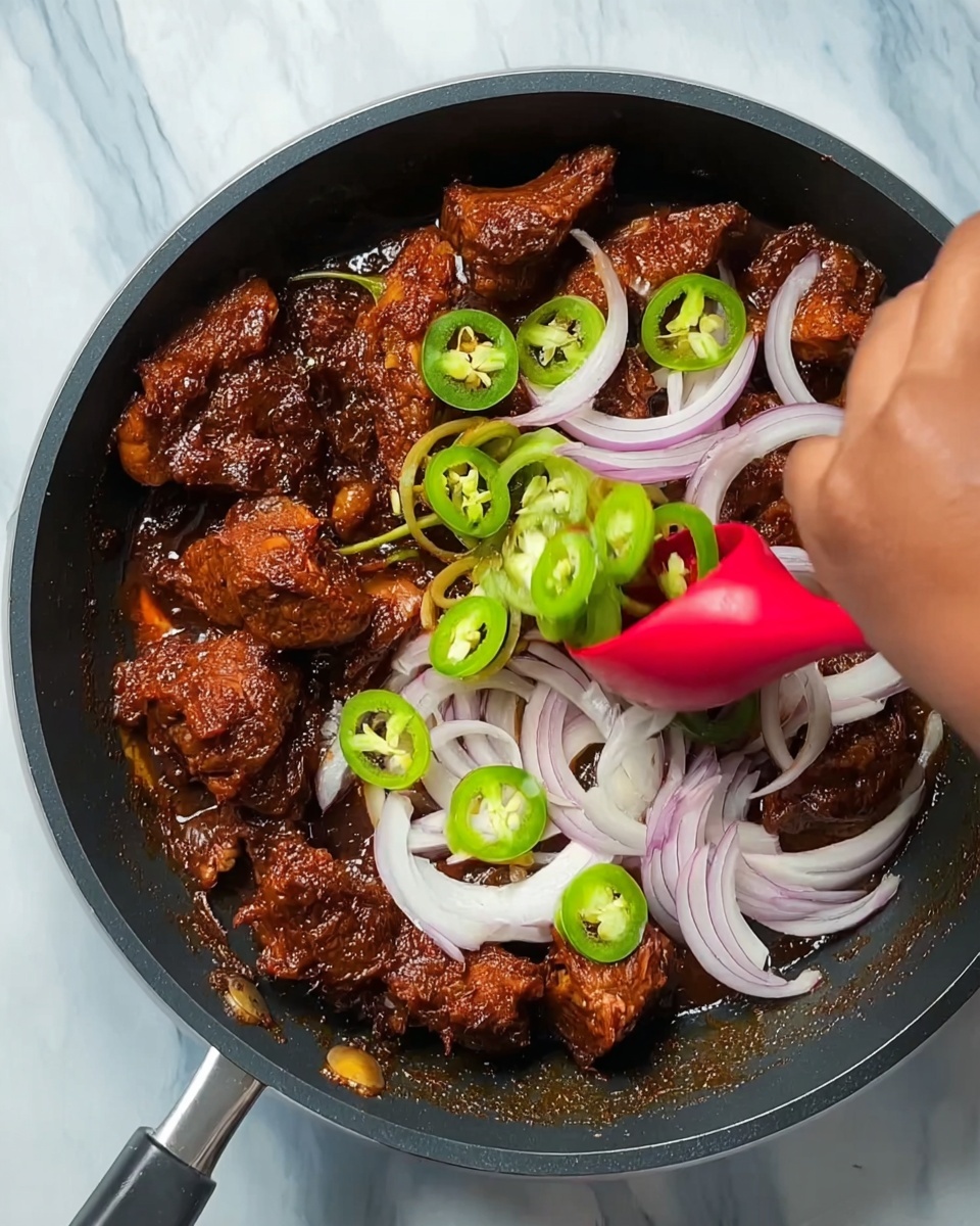 The image shows a black pan filled with dark reddish-brown cooked pieces of meat covered in sauce. On top, there are fresh onion slices in white and light purple colors and some sliced green chili peppers scattered over the meat. A red spoon rests inside the pan with a woman's hand adding the onions and chillies. The background has a white marbled texture. Photo taken with an iphone --ar 4:5 --v 7