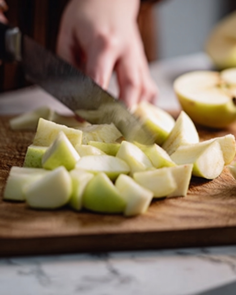 The image shows a close-up of a woman's hand holding a knife, slicing a pale green apple into uneven small pieces on a wooden chopping board. The apple pieces are scattered in front of the knife and appear fresh with smooth, light green skin and white flesh. The background features a blurred white marbled surface. The focus is mainly on the apple slices and the knife action, with soft natural light highlighting the scene. photo taken with an iphone --ar 4:5 --v 7