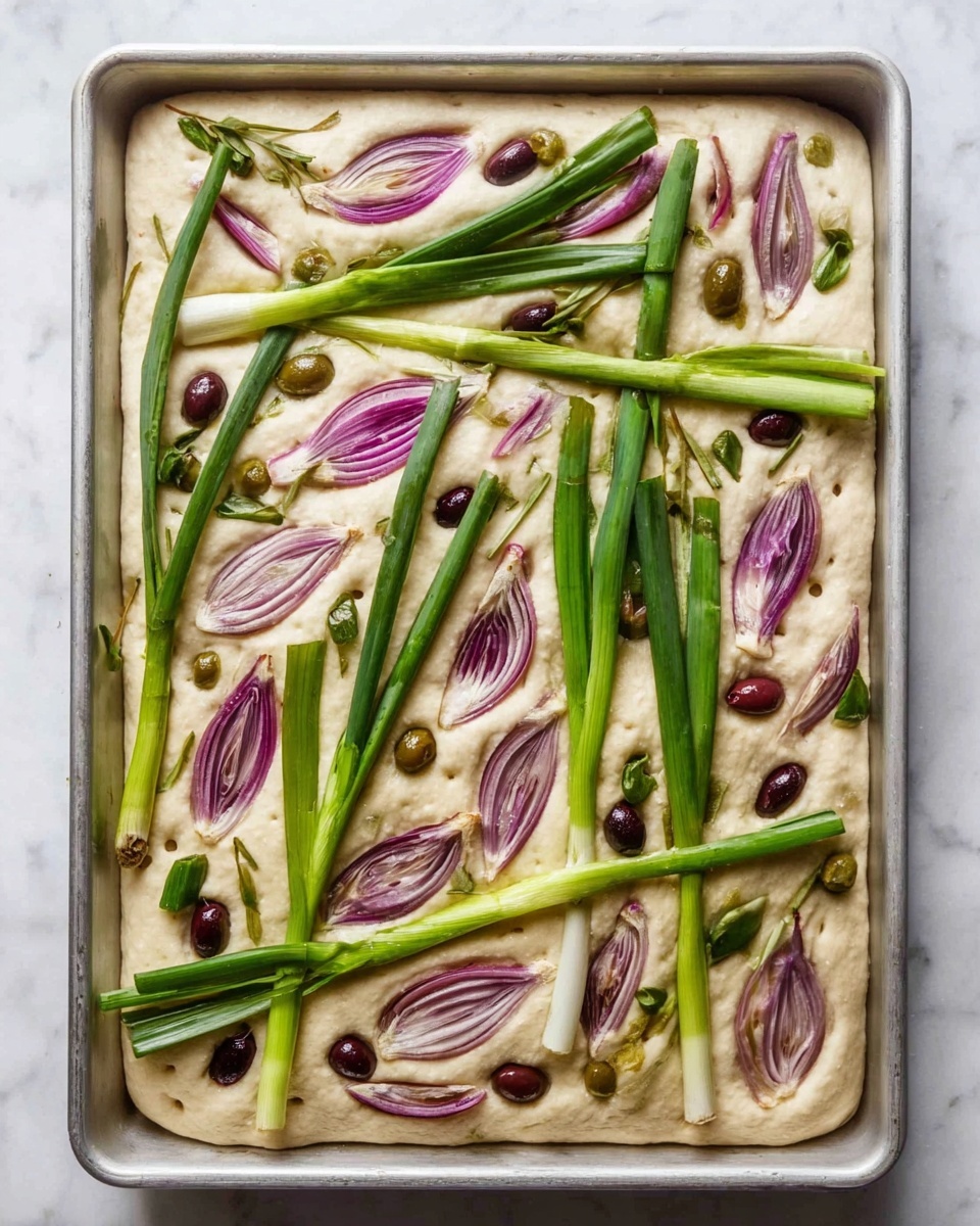 The image shows a rectangular focaccia dough in a baking tray on a white marbled surface. The dough is light beige with small dimples all over its surface. On top, there are several green onion stalks placed diagonally and vertically, with their green tops spreading out thinly. There are also multiple slices of purple-red onion scattered evenly across the dough, each slice showing smooth layers and a slight shine. Small round black olive slices are sprinkled all around, adding dark brownish spots. The colors of green onion stalks, purple onion slices, and dark olives contrast nicely against the pale dough. Photo taken with an iphone --ar 4:5 --v 7