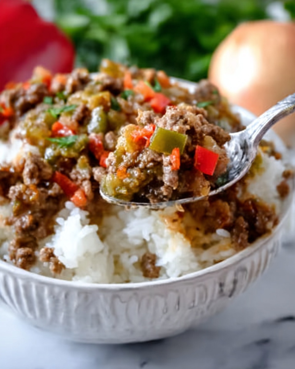 The image shows a close-up of white rice topped with a cooked mix of ground meat and diced vegetables that include red and green bell peppers. The food is served in a white bowl with a textured design. In the foreground, a spoon holds a bite of the rice and meat mixture, showing the moist texture of the cooked ingredients with small pieces mixed in. The background features a white marbled surface with hints of raw onion and parsley blurred out behind the bowl. photo taken with an iphone --ar 4:5 --v 7