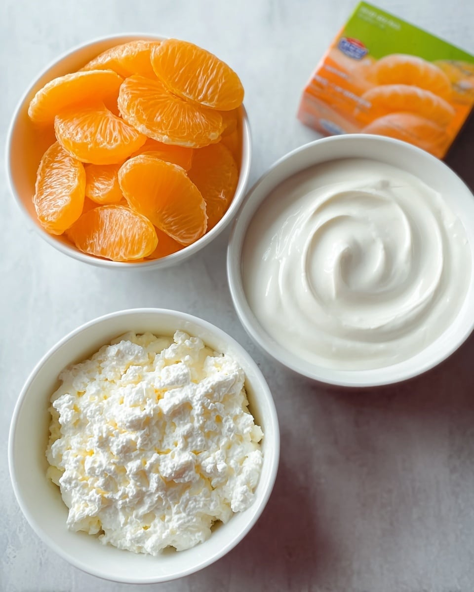The image shows three white bowls on a white marbled surface. The top left bowl holds bright orange mandarin orange slices stacked neatly. The top right container is full of thick, smooth white cream with a swirl pattern on top. The bottom left bowl has white cottage cheese with a slightly chunky and grainy texture. Next to the bowls, there is a colorful orange and green box. photo taken with an iphone --ar 4:5 --v 7