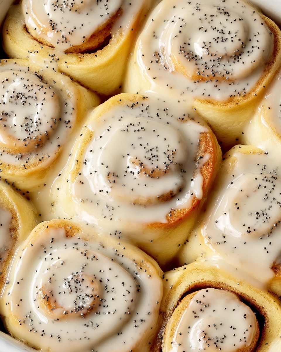 The image shows a close-up view of eight soft cinnamon rolls arranged closely in a white dish. Each roll has a light golden brown dough base that spirals inward with a smooth, thick, pale cream-colored icing spread over the top, slightly dripping along the edges. Tiny black poppy seeds are sprinkled evenly over the icing on each roll, adding a speckled texture. The rolls appear fluffy and slightly touching each other, with the glossy icing catching the light. The setting features a white marbled surface underneath the dish. photo taken with an iphone --ar 4:5 --v 7