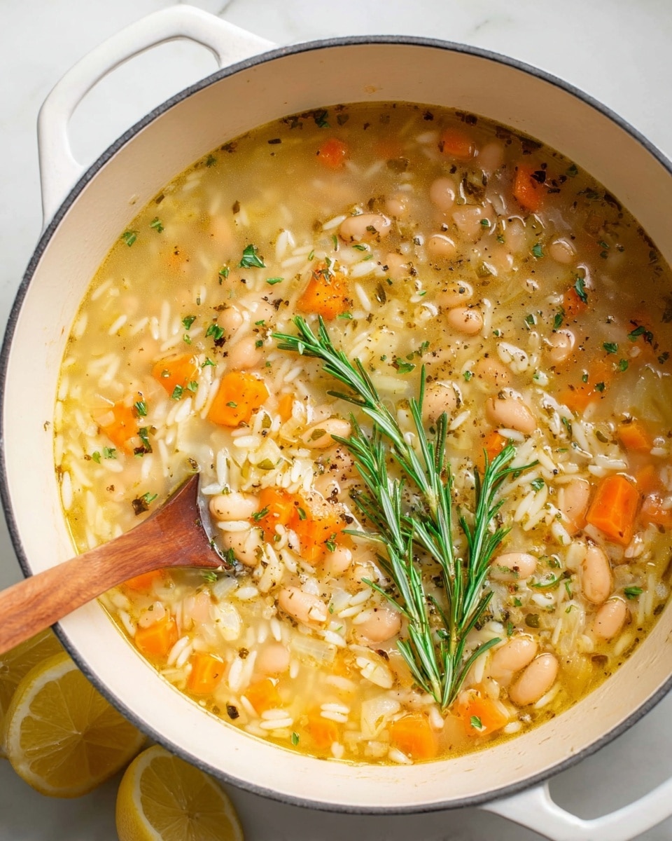 A white pot filled with a soup that has three main layers: a base broth that looks light yellow and clear, small chunks of orange carrot and small white beans spread evenly, and short white rice mixed throughout. The surface has tiny bits of green herbs sprinkled all over, black pepper specks scattered lightly, and two fresh green rosemary sprigs placed on top near the edge. The pot is placed on a white marbled surface with two lemon halves on the side. A wooden spoon partially dips into the soup from the left. Photo taken with an iphone --ar 4:5 --v 7