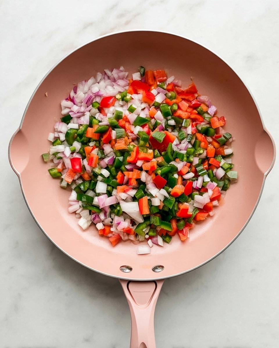 Inside a pink frying pan with a long handle, there are three layers of chopped vegetables spread evenly: white onions with a slightly translucent look, bright red bell peppers, and dark green chopped jalapeño peppers. The vegetables are small, cubed pieces mixed together showing a colorful contrast of white, red, and green. The frying pan sits on a white marbled surface, enhancing the fresh and vibrant colors of the vegetables. photo taken with an iphone --ar 4:5 --v 7