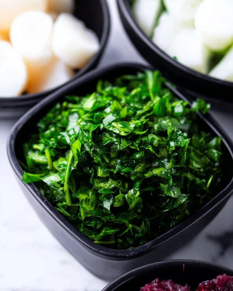 The image shows a close-up of a small black square bowl filled with bright green chopped herbs, which look fresh and leafy with a slightly wet texture. Next to it, there are parts of two other bowls visible: one with white round pieces that look soft and smooth, and another with some dark red or purple elements. The bowls are placed on a white marbled surface, creating a clean and simple background. The focus is mainly on the green herbs in the center bowl, showing their texture and color clearly. Photo taken with an iphone --ar 4:5 --v 7