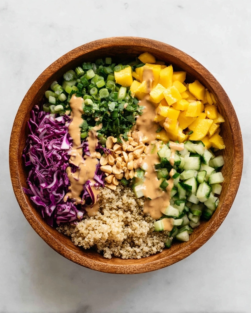 A wooden bowl on a white marbled surface contains a colorful salad with six distinct layers arranged side by side: finely chopped green onions at the top left, bright yellow mango cubes at the top right, medium green chopped cucumbers at the bottom right, light brown cooked quinoa at the bottom left, shredded purple cabbage in the middle left, and chopped fresh green herbs in the center. A creamy tan sauce is drizzled across the middle, covering parts of the quinoa, herbs, and mango, with a small pile of whole peanuts on the quinoa near the bottom. Photo taken with an iphone --ar 4:5 --v 7