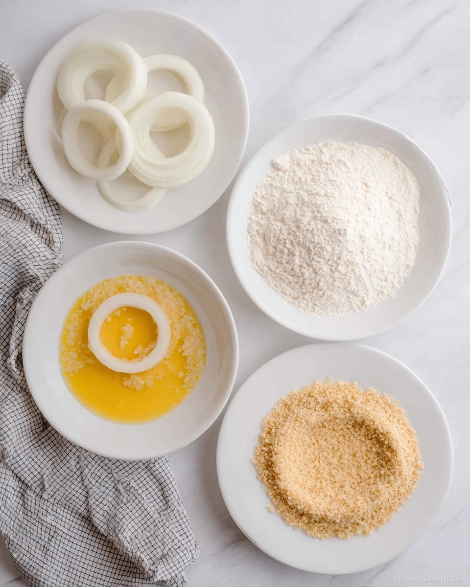 The image shows four white round plates arranged on a white marbled surface. The top left plate holds plain white onion rings. The top right plate contains a layer of white flour with one onion ring pressed into it. At the bottom left, a white bowl has a yellow beaten egg mixture with one onion ring halfway dipped in it. The bottom right plate has light brown breadcrumbs with one onion ring pressed inside. A folded grey and white checkered cloth is placed near the bottom left corner. Photo taken with an iphone --ar 4:5 --v 7