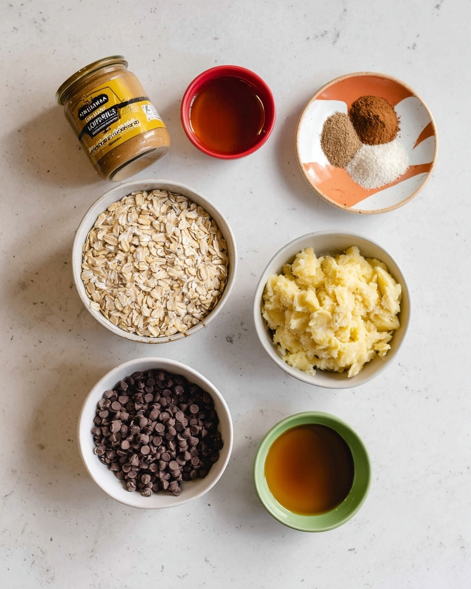 A white bowl filled with light tan rolled oats is in the center on a white marbled surface. Below it, a white bowl holds many small, dark brown chocolate chips, and next to it, a white bowl contains mashed yellow bananas. Above the oats, a small white plate with an orange and beige design holds some brown and white powders. To the left of the oats is a jar of smooth almond butter with a yellow and black label. Above the jar, a small red bowl has a little bit of a clear amber liquid. Below the bananas, a small green bowl contains more of the same amber liquid. Photo taken with an iphone --ar 4:5 --v 7