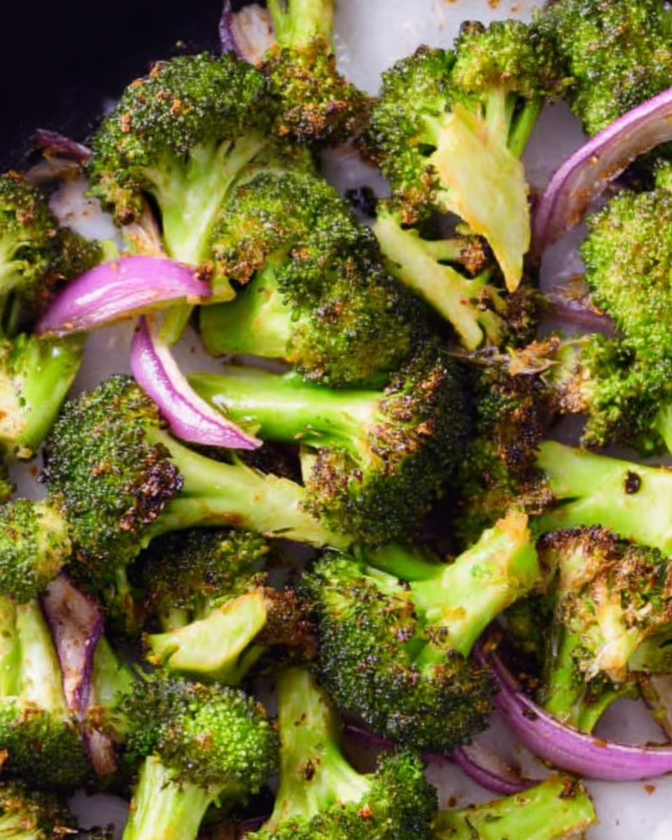 The image shows a close-up of roasted broccoli with a few thin slices of red onion mixed in. The broccoli pieces are bright green with slightly browned, crispy edges and a rough, textured surface. The red onion slices are pale purple with smooth, thin layers, scattered among the broccoli. All the food is placed on a white marbled surface, showing a natural and fresh look. Photo taken with an iphone --ar 4:5 --v 7