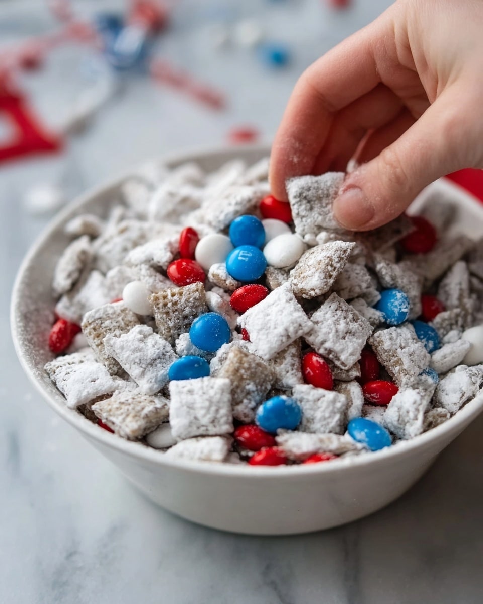 A white bowl filled with a snack mix that looks like small square pieces covered in white powder, mixed with red, blue, and white candy-coated chocolates scattered on top and inside. A woman's hand is reaching into the bowl, touching the snack pieces gently. The bowl sits on a white marbled surface. photo taken with an iphone --ar 4:5 --v 7