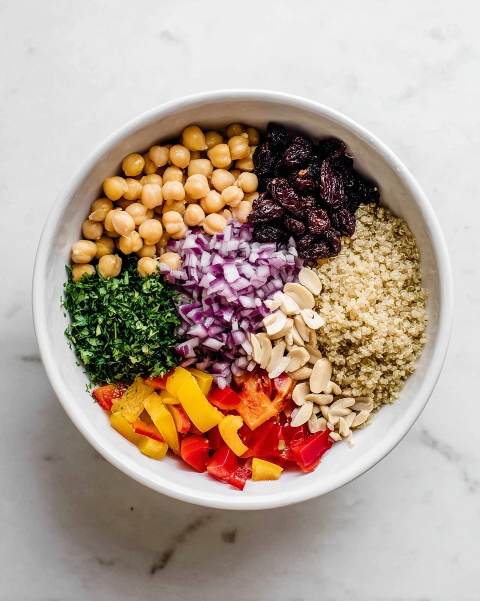 In a white bowl on a white marbled surface, there are seven visible layers arranged side by side. Starting from the top left is light yellow chickpeas, next to it finely chopped purple onions, followed by dark brown dried fruit pieces. To the right is a fluffy pale beige layer of quinoa. Below the dried fruit are thin sliced off-white nuts. Continuing to the left, there is a bunch of finely chopped fresh green herbs, and lastly, bright red and yellow bell pepper pieces at the bottom left. Each layer shows its texture clearly with neat separation. Photo taken with an iphone --ar 4:5 --v 7