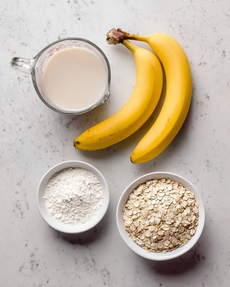 The image shows four ingredients arranged neatly on a white marbled surface. At the top left, there is a clear glass measuring cup filled with a light beige liquid, likely milk or a milk substitute. To the right of the cup, two bright yellow bananas with slightly brown tips lie side by side. Below these, on the left, is a small white bowl filled with a white powdery ingredient, possibly baking soda or baking powder. To the right of this bowl is another white bowl filled with off-white rolled oats, showing a rough and grainy texture. The overall look is simple and clean. Photo taken with an iphone --ar 4:5 --v 7