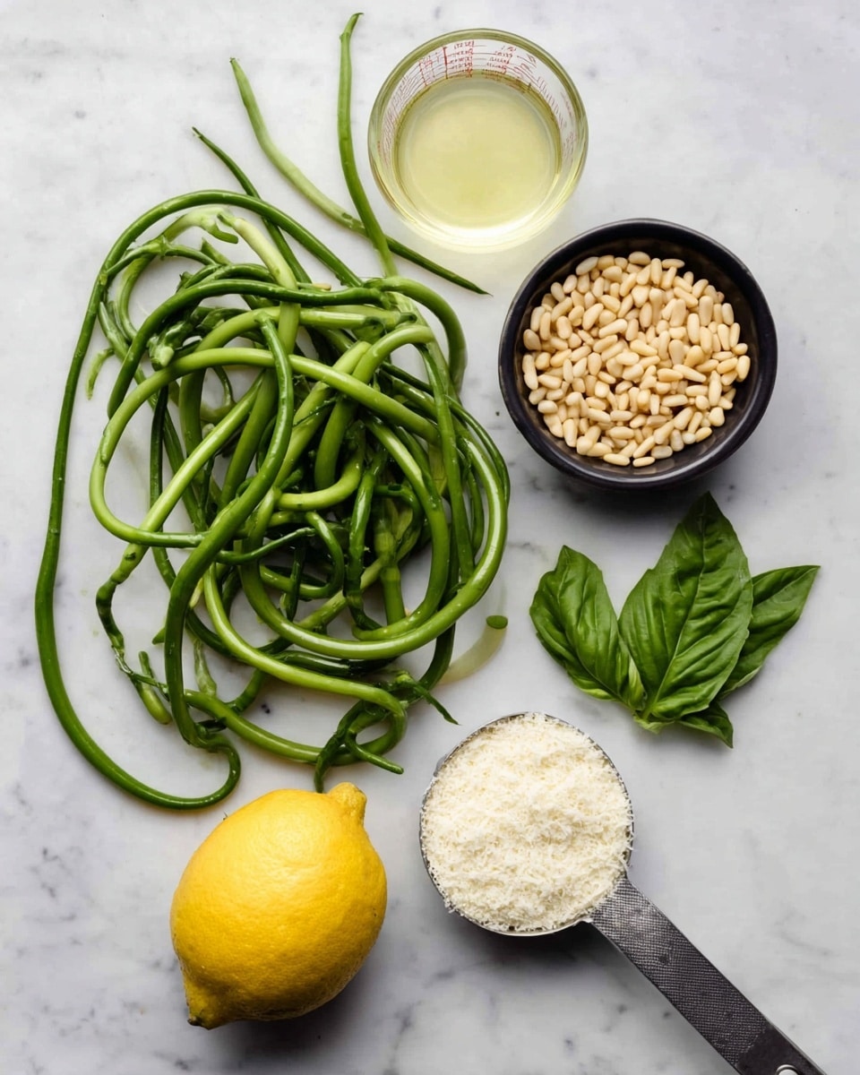 The image shows a top view of cooking ingredients neatly arranged on a white marbled surface. On the bottom left, there is a loose pile of long, twisted bright green garlic scapes with a fresh texture. Above it, to the right, there is a small black bowl filled with beige pine nuts. Directly to the right of the pine nuts, a few fresh green basil leaves lie flat. Below the basil and pine nuts, there is a whole yellow lemon with a smooth skin. On the bottom right, a metal measuring cup is filled with a white, powdery grated cheese. At the top left, there is a clear measuring cup containing a pale yellow liquid, likely oil. The layout is clean and organized, showcasing each ingredient’s texture and color clearly. photo taken with an iphone --ar 4:5 --v 7