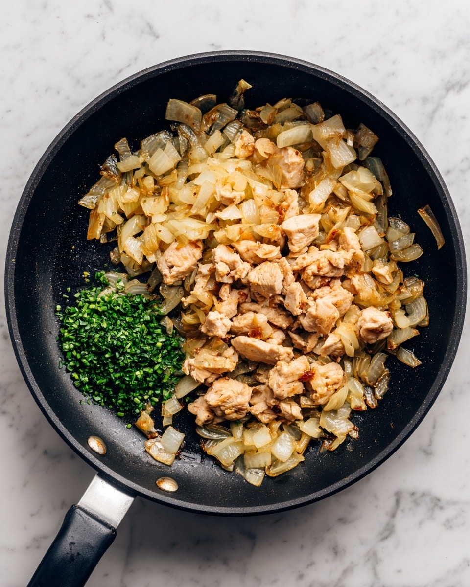 A black frying pan sits on a white marbled surface with cooked onions and a piece of light brown chicken in the center. The onions are golden and slightly caramelized with some pieces spread around the pan, forming no distinct shape, and some are lighter and some darker in color. A small pile of chopped green herbs is placed near the cooked chicken and onions, adding a fresh touch on the left side of the pan. The pan handle points downwards. photo taken with an iphone --ar 4:5 --v 7