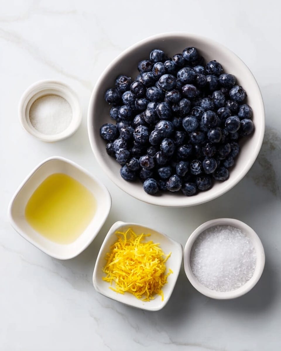 The image shows five white dishes on a white marbled surface. In the center, there is a round white bowl filled with fresh, dark blue blueberries. To the left, there are two small white square bowls; the top one contains a light yellow liquid, and the lower one holds bright yellow lemon zest. To the right of the blueberries, there is a small round white bowl with a white granulated substance, likely sugar, and above it, a tiny round white bowl with a white powder, possibly salt. The arrangement is neat and minimalistic, with soft natural light. Photo taken with an iphone --ar 4:5 --v 7