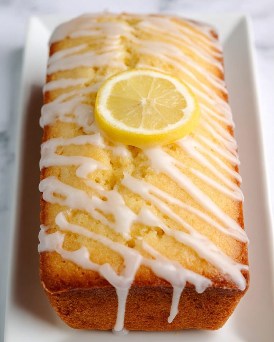 A rectangular lemon cake with a light golden brown crust and a soft, moist texture is shown from above. The cake has a thin layer of white icing drizzled in a zigzag pattern over the surface, creating a glossy, slightly thick coating that covers most of the top. In the center, there is a small, fresh lemon slice resting on the icing, adding a bright yellow color contrast. The cake sits on a white plate placed on a white marbled surface. photo taken with an iphone --ar 4:5 --v 7