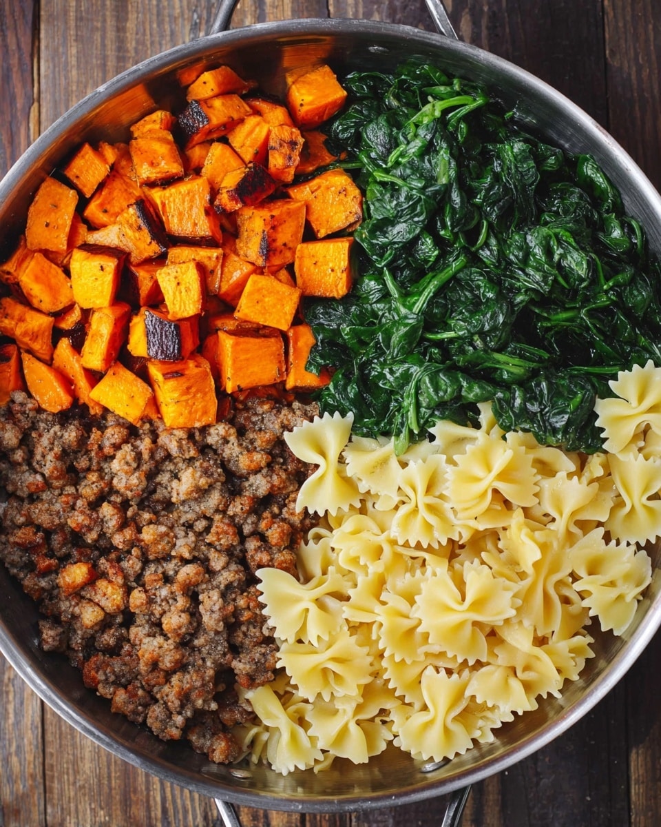 A round metal pan is filled with four different food sections evenly placed side by side. The top left section has small orange cubes of roasted sweet potatoes with some browned edges. The top right section shows a pile of cooked dark green spinach leaves with a shiny texture. The bottom left section contains browned cooked ground meat with a crumbly texture. The bottom right section holds pale yellow farfalle pasta with a smooth, firm look. The pan is on a wood surface. photo taken with an iphone --ar 4:5 --v 7
