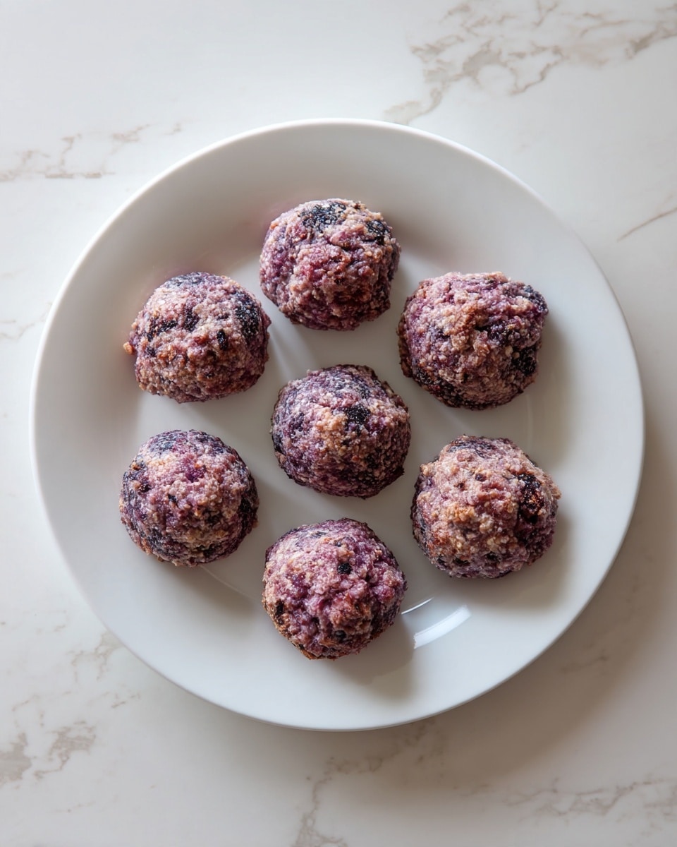 Seven round cookies with a rough, crumbly texture and a mix of purple and brown colors are arranged evenly on a plain white plate. The cookies have small darker spots and uneven tops, giving a rustic look. The plate sits on a white marbled surface with faint gray veins, creating a clean and simple background. photo taken with an iphone --ar 4:5 --v 7